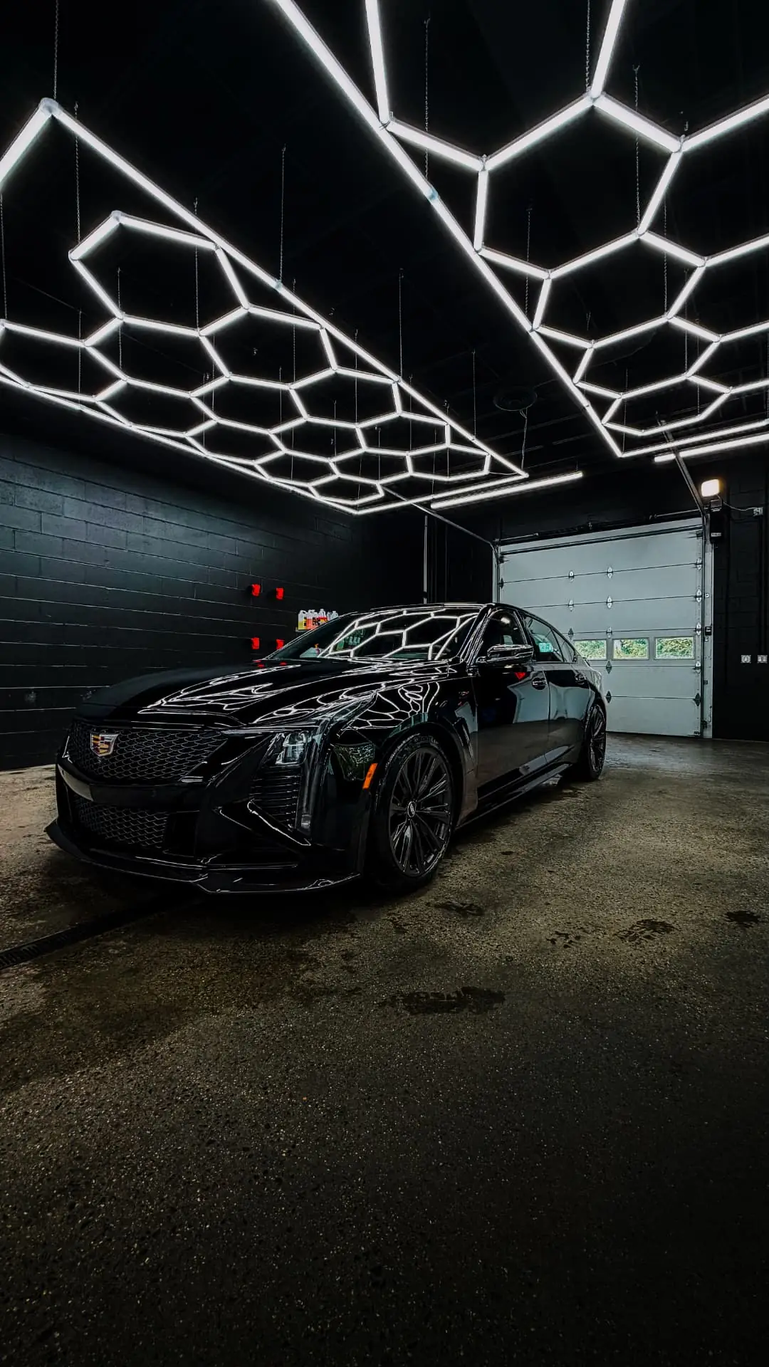 Black Cadillac CT5 under the hexagonal LED ceiling of the Luxury Signature Detailing studio in Danbury, CT